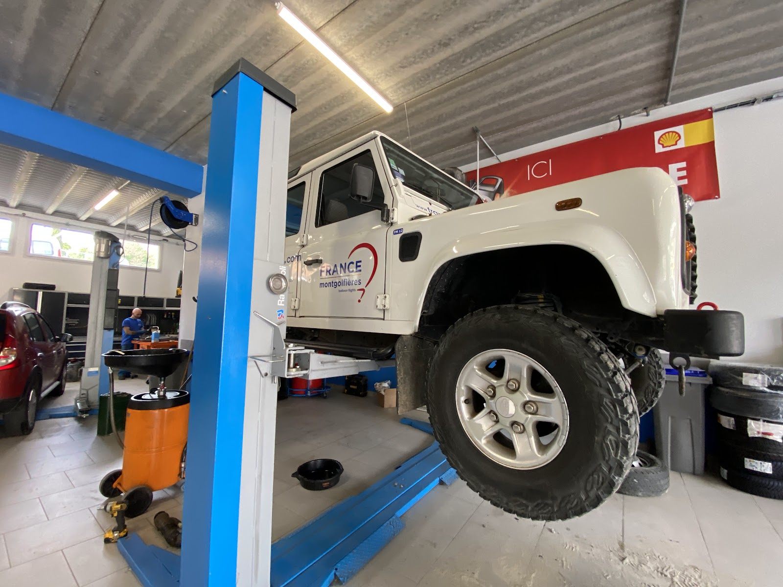 Land Rover Defender blanc sur le pont élévateur de l'atelier