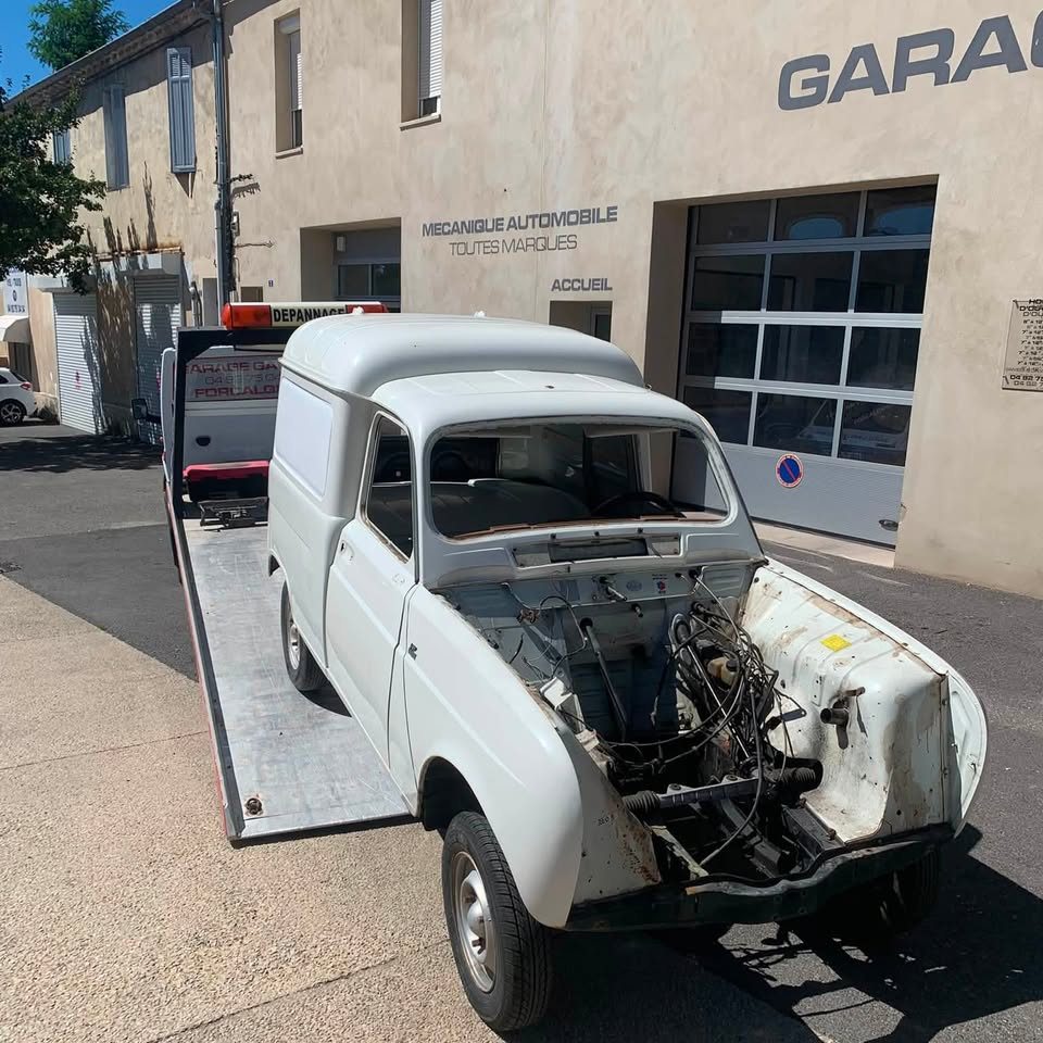 Renault 4 fourgonnette en cours de restauration, descendant du plateau de dépannage devant le garage