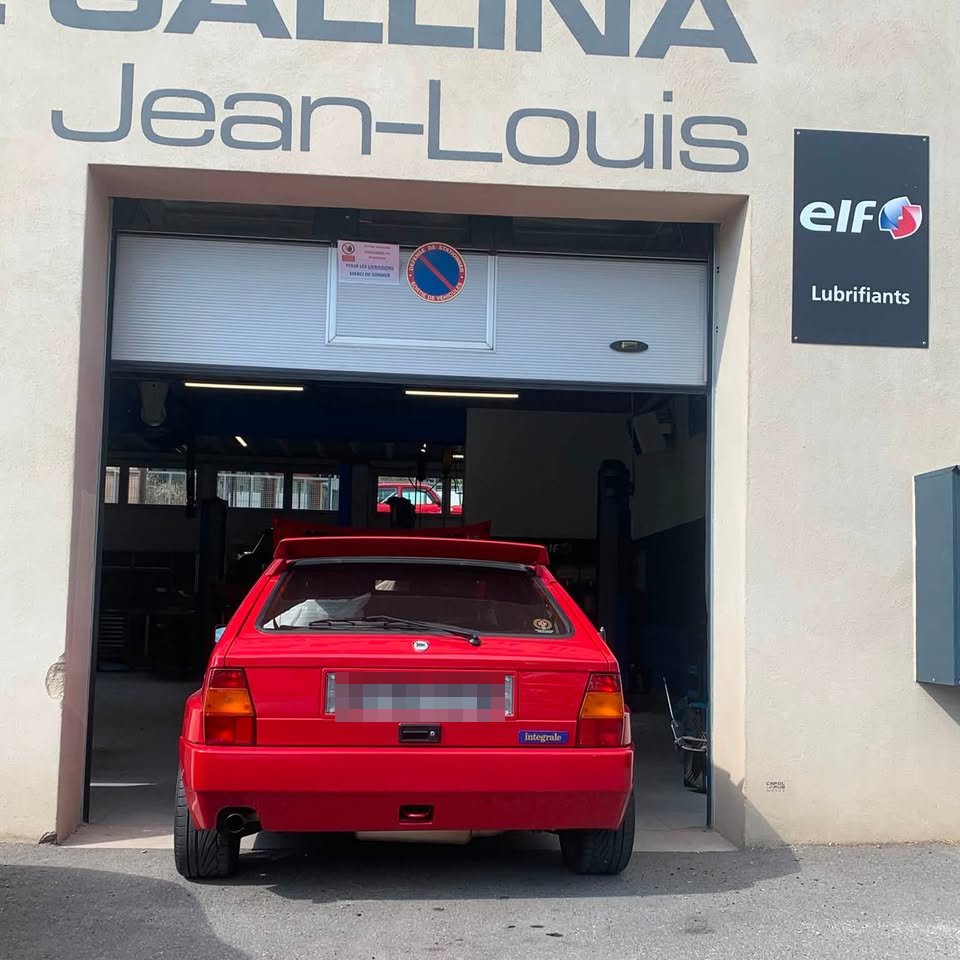 Lancia Delta Integrale rouge à l'arrière, garée dans l'atelier derrière la porte ouverte